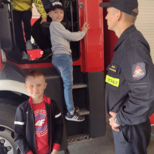 Pan Strażak prezentuje dzieciom wóz strażacki.