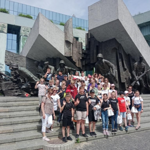 Uczniowie stoją pod Pomnikiem Powstania Warszawskiego