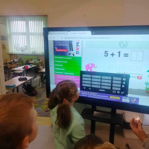 Uczennica klasy 1 rozwiązuje dodawanie na interaktywnym monitorze