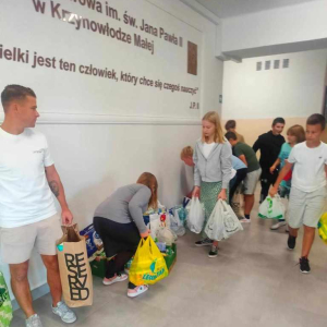 Opiekun Samorządu Uczniowskiego wraz uczniami pakuje dary by zawieźć do punktu zbiórki.