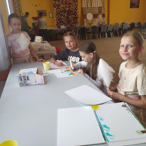 Dziewczynki malują przy stolikach.