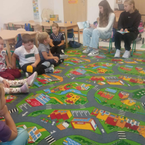 Starsze dziewczynki czytają młodszym dzieciom.