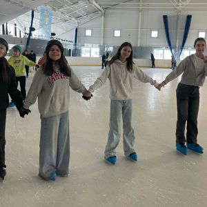 dziewczynki trzymające się za ręce, jeżdżą na łyżwach