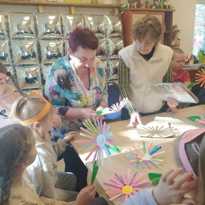 Seniorki pomagają w tworzeniu kwiatków.